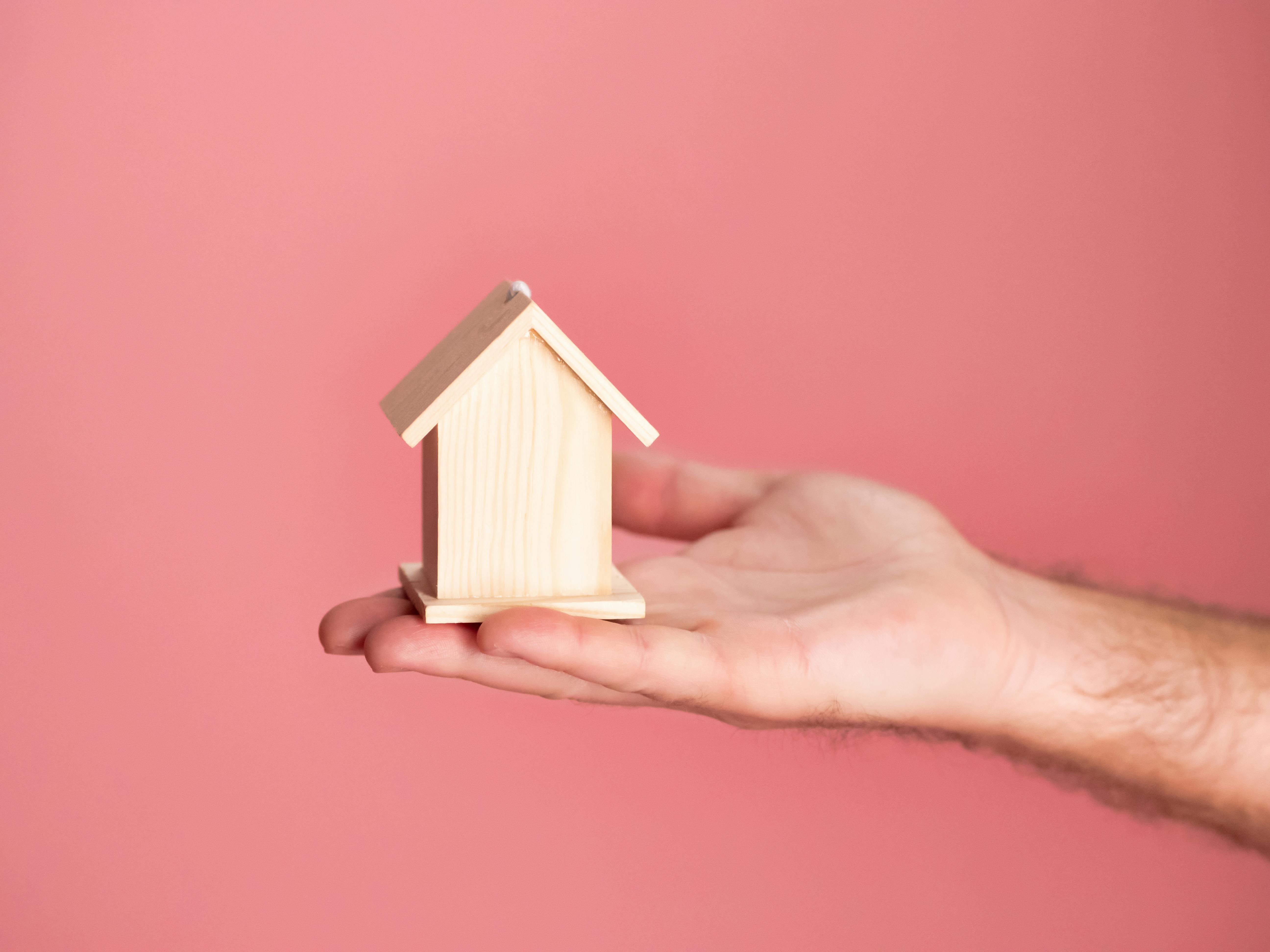 a person holding a small wooden house for Mortgages in Indiana